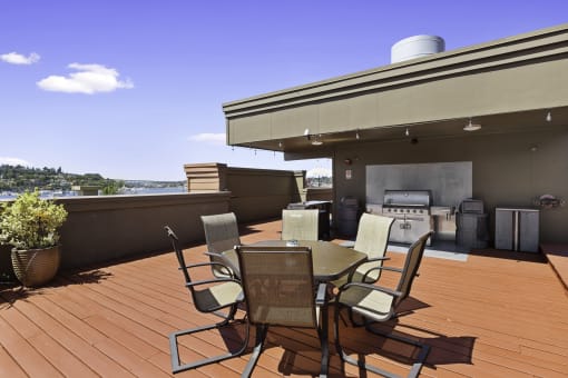 Rooftop patio area with a table and lounge chairs and a grill at Illumina Apartment Homes, WA 98102
