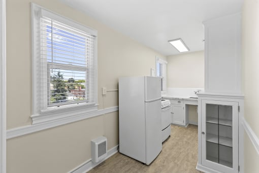 View of the kitchen with a refrigerator, white cabinets with glass pane, and a sink at Malloy Apartment Homes in Seattle, 98105