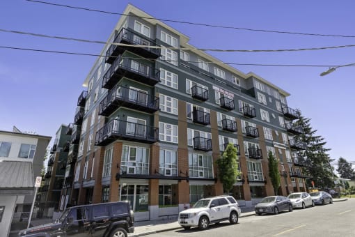 Multi-story property building on the street with cars parked in front of it at Sedona Apartments, Seattle, WA
