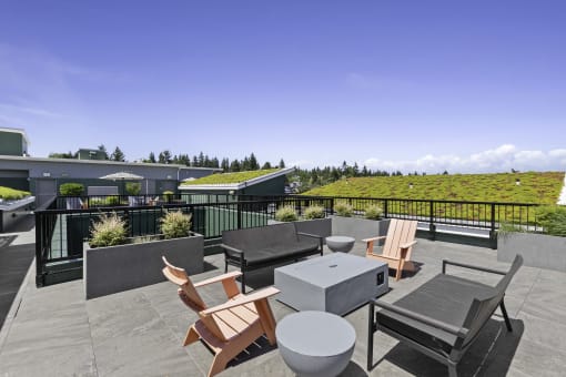 a rooftop resident patio with tables and chairs and a grassy space in the background at Sedona Apartments, Seattle, 98115