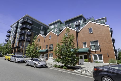a view from the street of a large apartment complex with cars parked in front of it  at Sedona Apartments, Seattle, WA, 98115