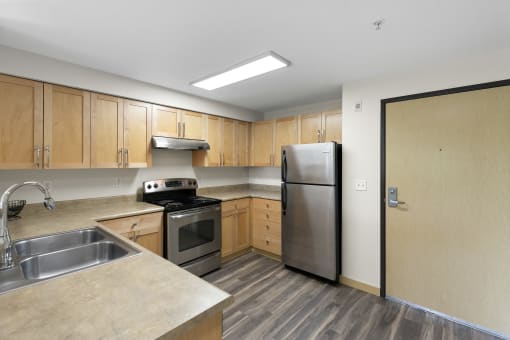 a kitchen with wooden cabinets and stainless steel appliances at Villaggio Apartment Homes, WA 98402
