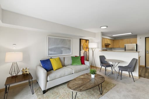 a living room with a couch, table, and a bistro set and a kitchen in the background at Villaggio Apartment Homes, Tacoma, WA