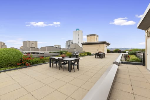 Resident Rooftop Lounge with tables and chairs and a view of the city at Villaggio Apartment Homes, Tacoma, Washington 98402