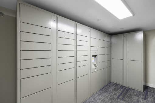 White Package Receiving Lockers in a room with a gray carpet at West Mall Place Apartment Homes, Everett