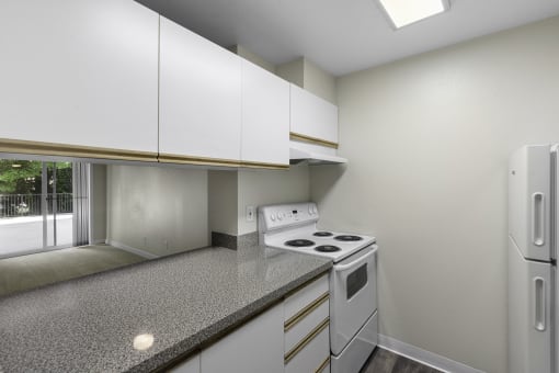 Cozy kitchen with white cabinets, overhead lighting, and white appliances at West Mall Place Apartment Homes, Everett, 98208