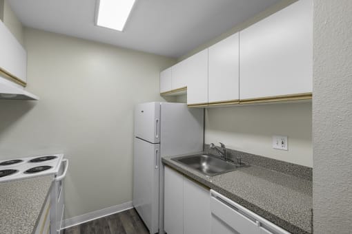 a kitchen with white cabinets and sink  at West Mall Place Apartment Homes, Everett