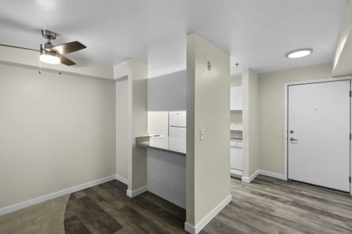 Dining Area with Plank Flooring, and overhead ceiling fan with light and view into kitchen from breakfast bar at West Mall Place Apartment Homes, Everett, WA, 98208