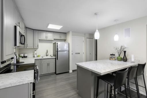 an open kitchen with a large island, plank flooring, and stainless steel appliances at Willows Court Apartment Homes, Seattle