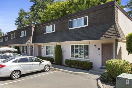 Side View of Townhome Buildings with White Walls, Manicured Shrubs, and Resident Reserved Parking at Woodlake Townhomes, Washington