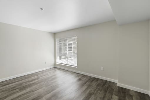 a bedroom with hardwood flooring and a large window at Excalibur Apartment Homes, Bellevue, Washington 98004