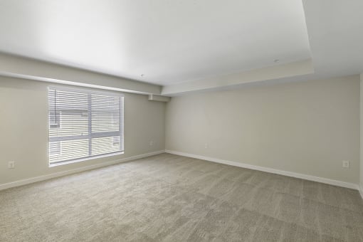 Spacious Living Area with Large, Oversized Windows with Blinds and Tan Plush Carpeting Wall to Wall at Excalibur Apartment Homes, Bellevue, Washington 98004