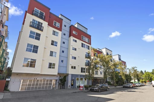 an apartment building with a parking lot in the foreground and a blue sky in the background