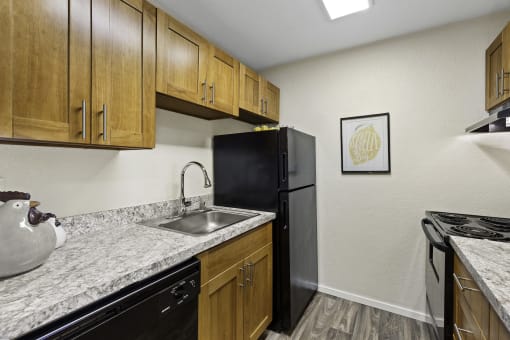a kitchen with wooden cabinets and granite countertops at Pacific Park Apartment Homes, WA 98026