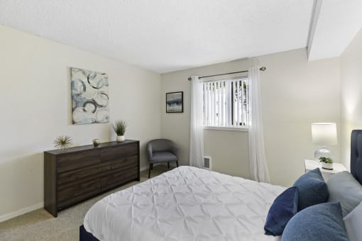 a bedroom with a large bed and a dresser with a chair at Pacific Park Apartment Homes, Washington, 98026