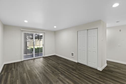 Large Open Floor Living Space with Dark Plank Flooring and Wide Sliding Glass Doors Leading Outside at Park 210 Apartment Homes, Edmonds, WA
