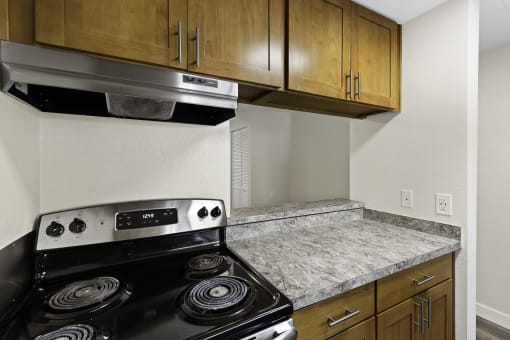 A Kitchen with Wood Cabinets and a Stove Top Oven at Park 210 Apartment Homes, Edmonds, WA