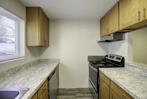 a kitchen with wooden cabinets and granite countertops at Park 210 Apartment Homes, Edmonds, Washington