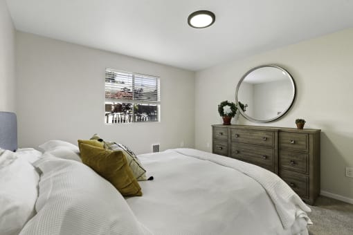 a bedroom with a large bed and a dresser with a mirror