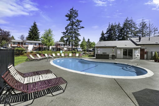 Large Pool with Lounge Chairs and Trees in the Background at Pinewood Square Apartment Homes, Washington, 98087