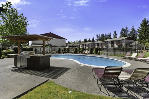 Sparkling Swimming Pool with a Spa and Lounge Chairs in Front of the Resident Grilling Station at Pinewood Square Apartment Homes, Washington