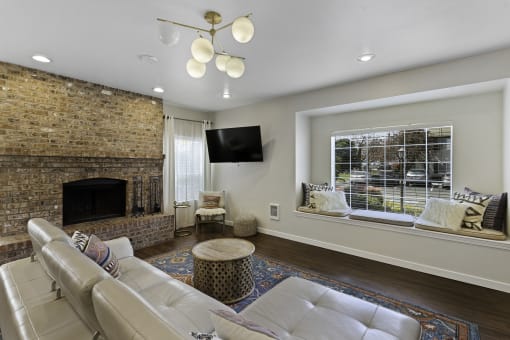 Spacious Living Room with a stone fireplace and river rock mantle with a large window at Serra Vista Apartment Homes, Lynnwood, 98087
