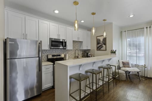 Stunning Kitchen with effieincet appliance, pendant lighting, and bar stool seating at Serra Vista Apartment Homes, Lynnwood, WA