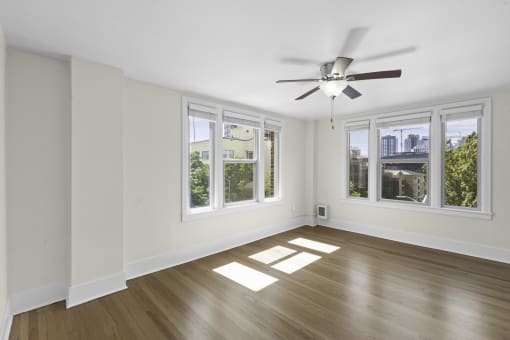 an empty living room with a ceiling fan and five windows at Stockbridge Apartment Homes, Seattle, 98101
