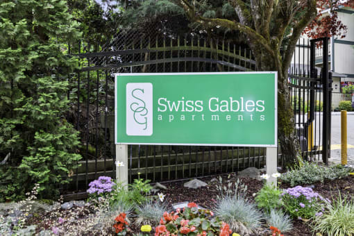Swiss Gables Property Sign with Multicolor Flowers Underneath it at Swiss Gables Apartment Homes, Kent