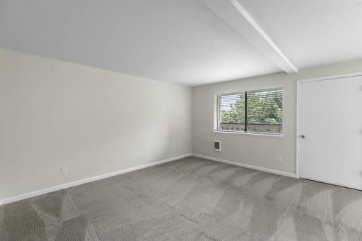 an empty bedroom with a window and a door at Swiss Gables Apartment Homes, Kent, 98032