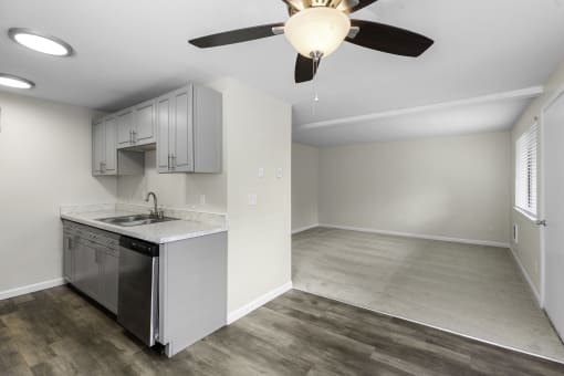 a kitchen with Plank Flooring and Recessed Lighting, Dining Room with Overhead Ceiling Fan with Light, and Living Room  with Grey Carpeting at Swiss Gables Apartment Homes, Kent, 98032