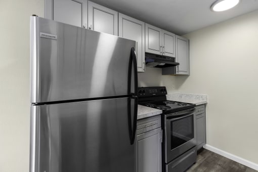a kitchen with stainless steel appliances and white cabinets at Swiss Gables Apartment Homes, Kent, Washington 98032
