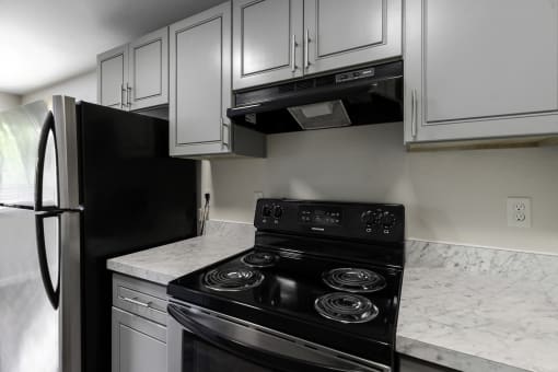 a kitchen with white cabinets and black appliances at Swiss Gables Apartment Homes, Kent, 98032