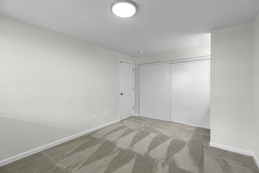 a bedroom with white walls, gray carpet, and overhead lighting at Swiss Gables Apartment Homes, Kent, 98032