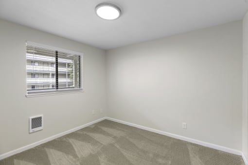 a bedroom with white walls and a window at Swiss Gables Apartment Homes, Kent