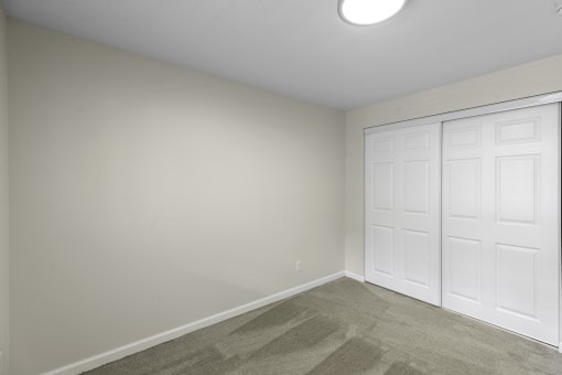 a bedroom with two closet doors and a carpeted floor at Swiss Gables Apartment Homes, Kent, WA