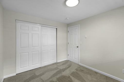 a bedroom with two closet doors and a carpeted floor at Swiss Gables Apartment Homes, Kent, 98032