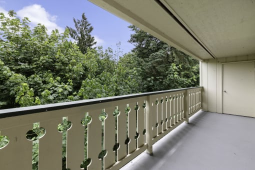 a balcony with trees in the background at Swiss Gables Apartment Homes, Kent, WA