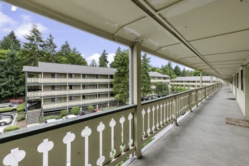 a balcony with a white fence and a large building in the background at Swiss Gables Apartment Homes, Kent, 98032