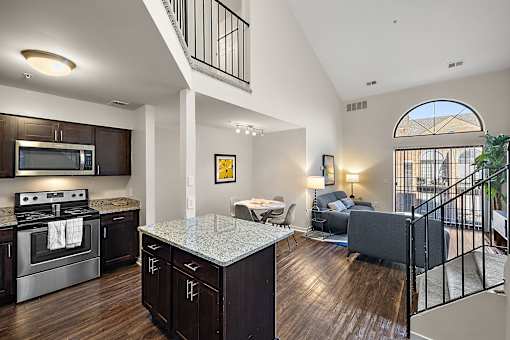 A modern kitchen with dark wood floors and a large island at MainCentre, Northville