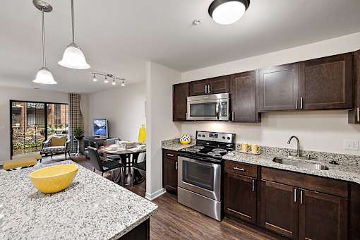 A modern kitchen with granite countertops and stainless steel appliances at MainCentre, Northville