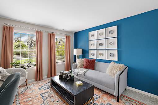 A living room with a grey couch, a coffee table, and a window with curtains at Briarcliff Village, Michigan, 48390