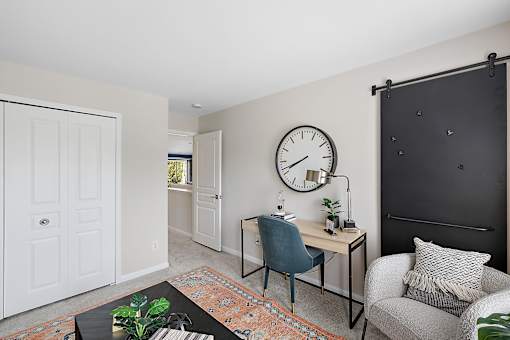 A room with a desk, chair, and clock on the wall at Briarcliff Village, Michigan, 48390