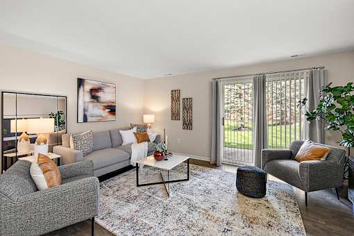 A living room with a grey couch, a grey armchair, a coffee table, and a rug at Briarcliff Village, Michigan, 48390