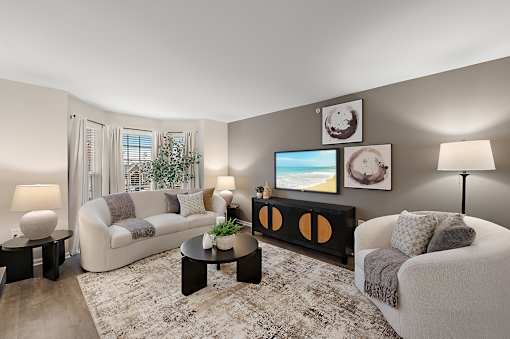 A living room with a couch, a chair, a coffee table, and a painting on the wall.