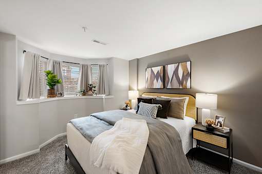 A bedroom with a large bed and a window with curtains.