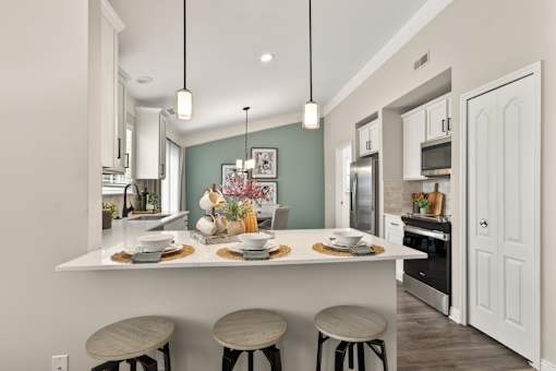 A kitchen with a white counter and three stools.