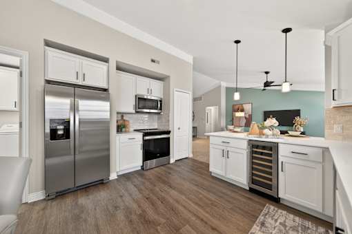 A modern kitchen with a refrigerator, microwave, oven, and a dining table.