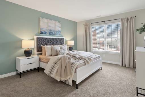 A bedroom with a bed, nightstand, and window.