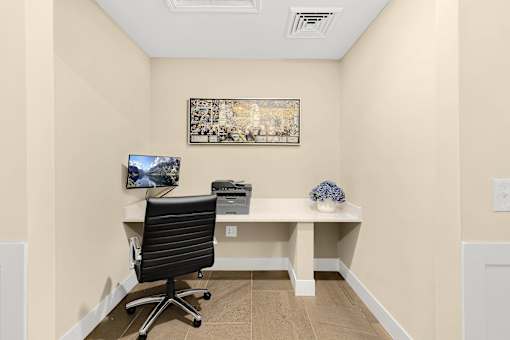 A black office chair is in front of a desk with a computer monitor and a framed picture on the wall at Briarcliff Village, Michigan, 48390